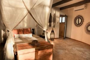 a bedroom with a canopy bed with a wooden table at Chobe House Villa and Chalets in Kasane