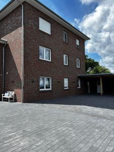 ein Backsteingebäude mit weißen Fenstern und einer Terrasse in der Unterkunft Ferienwohnung Harms, 85116 in Ostrhauderfehn + 3 Fotos