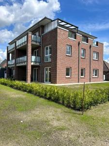 ein rotes Backsteingebäude mit vielen Fenstern in der Unterkunft Ferienwohnung Harms, 85116 in Ostrhauderfehn