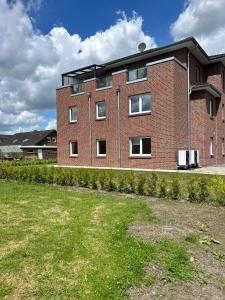 ein rotes Backsteingebäude mit einem Hof davor in der Unterkunft Ferienwohnung Harms, 85116 in Ostrhauderfehn