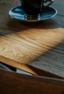 a cup of coffee on a plate on a wooden table at 5分車程札幌中心大通公園 豐平川河景四房 廁所x2 浴室x1 淋浴x1 包棟別墅近地鐵 停兩台車 in Sapporo