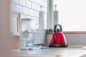 a red tea kettle sitting on a kitchen counter at 5分車程札幌中心大通公園 豐平川河景四房 廁所x2 浴室x1 淋浴x1 包棟別墅近地鐵 停兩台車 in Sapporo