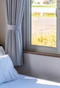 a window with a curtain and a bed next to it at 5分車程札幌中心大通公園 豐平川河景四房 廁所x2 浴室x1 淋浴x1 包棟別墅近地鐵 停兩台車 in Sapporo
