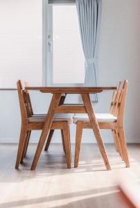 a wooden table and two chairs sitting next to a window at 5分車程札幌中心大通公園 豐平川河景四房 廁所x2 浴室x1 淋浴x1 包棟別墅近地鐵 停兩台車 in Sapporo