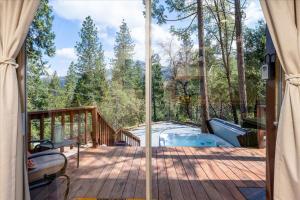 Una terraza cubierta con vista al bosque. en Tiny home with spa/firepit/and more, en Yosemite Forks