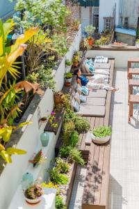 a balcony garden with plants and people laying on benches at Boavista Guest House in Porto