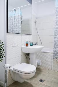a white bathroom with a toilet and a sink at Maria - Modern Apartment with Parking and Workspace in Bucharest