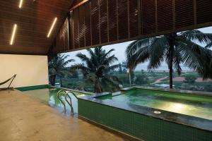 a swimming pool with a view of a palm tree at Infinity Beach Villa by EWA Properties in Manjeshwara