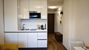 a kitchen with white cabinets and a sink at Hostdomus - Yellow Suite in Sestriere