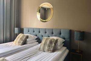 a bedroom with a bed with a blue headboard and a mirror at Hotel Golden Circle Suites in Rovaniemi