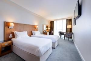 a hotel room with two beds and a desk at Glashaus Hotel in Tallaght