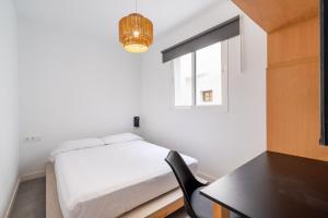 a bedroom with a bed and a desk and a window at Tiendas 26 in Almería