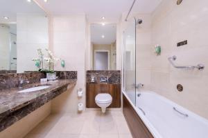 a bathroom with a tub and a toilet and a sink at Glashaus Hotel in Tallaght