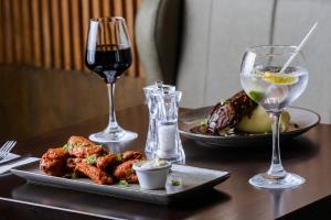 a table with a plate of food and two glasses of wine at Glashaus Hotel in Tallaght