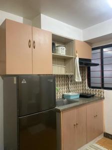 a kitchen with a black refrigerator and wooden cabinets at comfy Deca homes hernan cortes near sm jmall in Mandaue City
