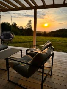 a couple of chairs sitting on a deck with the sunset at Chatka ChoćCo in Ryglice