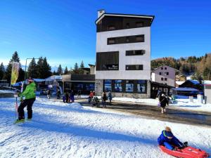 un grupo de personas en la nieve frente a un edificio en Hotel Arlecchino - Dada Hotels, en Madesimo