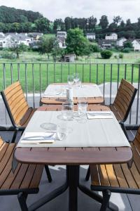 a wooden table with two chairs and wine glasses at La Différence in Vichten