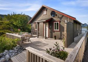 a wooden cabin with a deck and a bench at Sildpollnes Lodge in Vestpollen