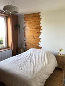 a bedroom with a white bed and a wooden wall at La loc donvillaise in Donville-les-Bains