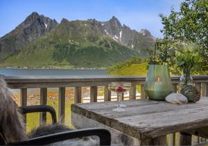 a table with a glass of wine and flowers on a balcony at Sildpollnes Lodge in Vestpollen