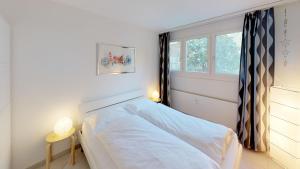 Un dormitorio con una cama blanca con una ventana. en Unique Serviced Living at Basel Waterfront 9001, en Basilea