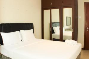 Un dormitorio con una gran cama blanca y un espejo. en Great Location and Comfy 2BR Apartment at Thamrin Residence By Travelio, en Yakarta 14 fotos más