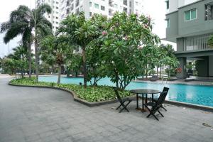 Una mesa y sillas junto a una piscina en un edificio. en Great Location and Comfy 2BR Apartment at Thamrin Residence By Travelio, en Yakarta