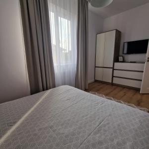 a bedroom with a white bed and a window at Apartament Marco 5 in Baia Mare