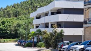 a white building with cars parked in a parking lot at Appartement Ponte de lima in Ponte de Lima