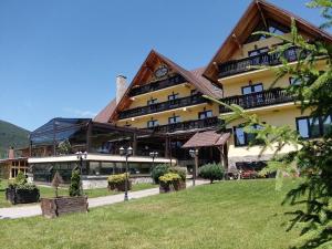 a large building with a green lawn in front of it at Resort Sf Petru - demipensiune in Tău Bistra