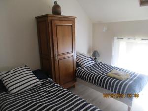 a bedroom with two beds and a wooden cabinet at Soir en Sologne in Neuvy-sur-Barangeon