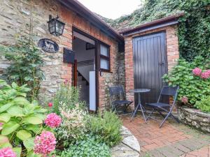 un giardino con due sedie e un tavolo di fronte a un edificio di Coach Cottage a Colyton