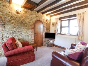 un soggiorno con 2 sedie e una TV di Coach Cottage a Colyton