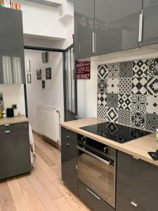 una cocina con armarios negros y una pared de azulejos en Appartement Cosy tout équipé, en Colombes 2 fotos más