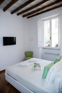 a white bedroom with a large white bed and a television at PgrHome Luxury Apartments Parione in Rome
