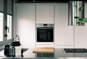 eine Küche mit weißen Schränken und einem Herd mit Backofen in der Unterkunft ComeCasa Terraced Apartment in Porta Romana in Mailand + 29 Fotos