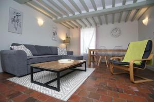 a living room with a couch and a table at LA FERME DE LONGUES maisons spécialisées pour les familles avec jeunes enfants in Longues-sur-Mer