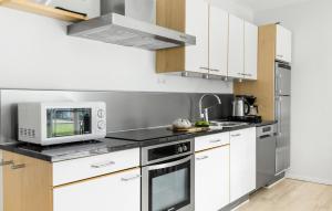 a kitchen with white cabinets and a microwave at Gudhjem Søpark Lejl 33 in Gudhjem