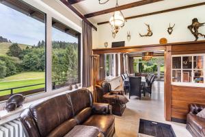 sala de estar con muebles de cuero y ventanas grandes. en Zum Holzknecht, en Willingen
