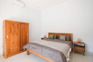 Un dormitorio con una cama y un armario de madera. en Stargazer Villa, en Canggu