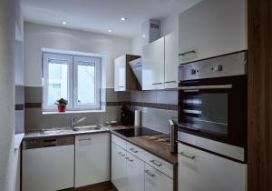 a kitchen with white cabinets and a sink and a window at Boardinghouse Apart-Hotel in Oberkochen