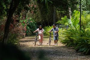 zwei Personen schieben ihre Fahrräder einen Weg entlang in der Unterkunft SaffronStays Biccode Woodside Heritage in Belūr