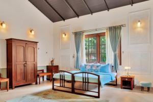 ein Wohnzimmer mit einem blauen Sofa und einem Fenster in der Unterkunft SaffronStays Biccode Woodside Heritage in Belūr