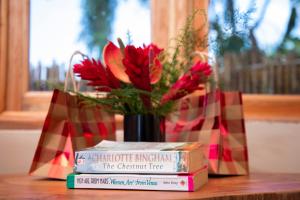 a vase with flowers and books on a table at Kaswa Lodge in Fort Portal