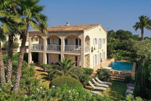 a large house with a swimming pool and palm trees at Villa AMOROS in Alcudia