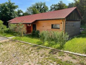 a small wooden cabin with a red roof at Gästewohnung am Schlosspark Hohenprießnitz in Hohenprießnitz