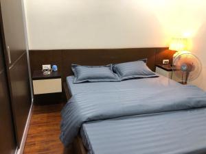 a bedroom with a bed with blue sheets and a lamp at Happy Apartment-SHP Plaza Lạch Tray in Hai Phong