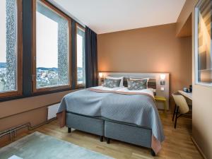 ein Schlafzimmer mit einem Bett und zwei Fenstern in der Unterkunft Quality Hotel 33 in Oslo
