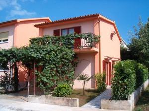 ein rosa Haus mit vielen Pflanzen davor in der Unterkunft Apartment Valbandon, Istia 2 in Fondole